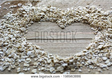 Raw brown cereals in heart form are on the wooden background