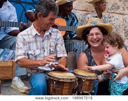 HAVANA April 2011 Cuba: very folkloric street musicians at Havana, playing Caribbean music for so many tourists visiting the Plaza de la Catredal. Mom and the little daughter play percussion