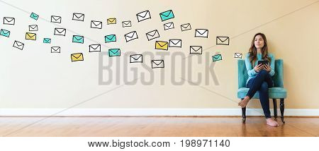 Emails with young woman holding a tablet computer in a chair
