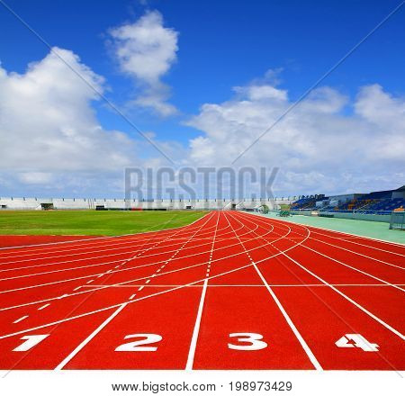 Sport running track. Lanes 1 2 3 4 of a red racing track with blue sky background image for design and other.