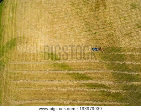Tractor pulling a hay rake to prepare for baling.