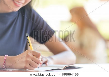 happy student girl write books outdoor.Female student taking notes from a book at library.