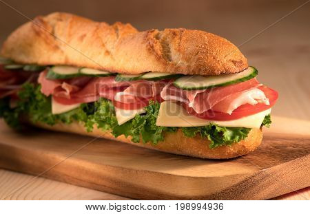Fresh crispy sandwich with prosciutto cheese tomatoes lettuce cucumbers on a wooden background.Close Up. Healthy concept.