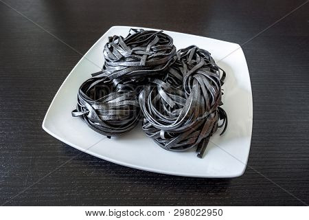 Dry Black Pasta With Cuttlefish Ink. Pasta Of Durum Wheat Semolina With Squid Ink On A Square Plate
