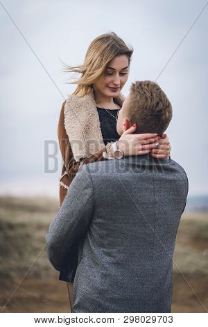 Beautiful Lovely Couple In The Park Or Field Or Track. Man In Coat And Scarf With Girl In Coat. Man 