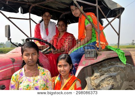 Close Up Front View Of Five Young Girls Sitting On A Tractor Wearing Colorful Salwar Kameez In A Fie