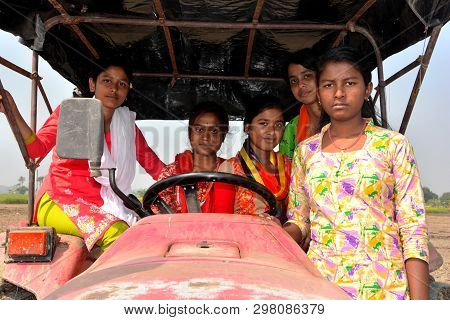 Close Up Front View Of Five Young Girls Sitting On A Tractor Wearing Colorful Salwar Kameez In A Fie