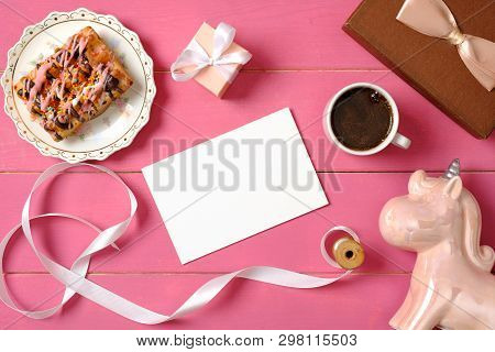 Hipster Girls Accessories On Pink Wooden Desk: Blank Paper Card, Ribbon, Unicorn, Cup Of Coffee, Gif