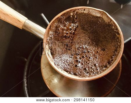 Barista Preparing Hot Tasty Drink From Copper Turk, Boils Water For Coffee On Small Fire In Cezve. C