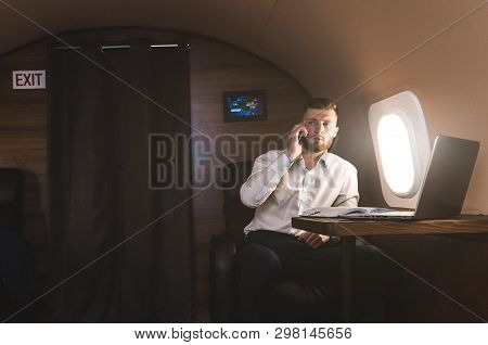 Young Attractive And Successful Businessman Talking On The Phone And Working While Sitting In The Ch