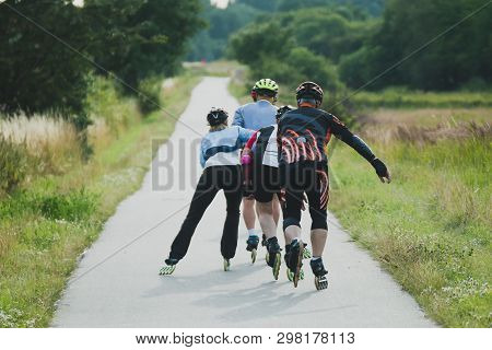 Four Older People Riding On Roller Skates In Line