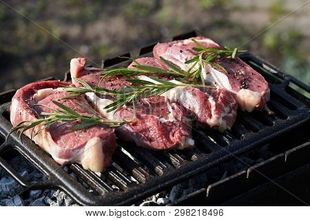 Cooking Outdoors. Raw Juicy Beef Steaks With Rosmary On Grill.