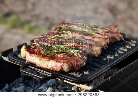 Cooking Outdoors. Juicy Beef Steaks With Rosmary On Grill.