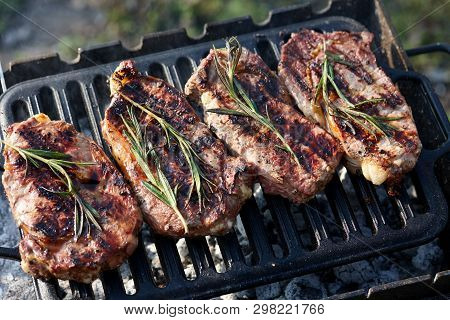 Cooking Outdoors. Juicy Beef Steaks With Rosmary On Grill.