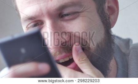 A Young Bearded Man Uses His Mobile Phone. Close-up Shot, Focus On Eyes.