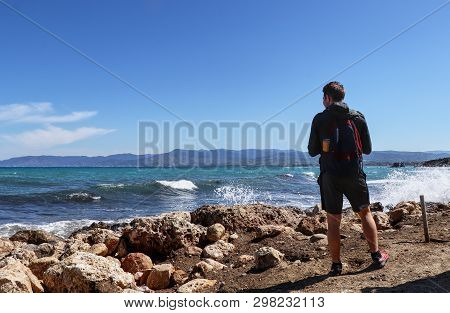 Younger Boy Stands On Seashore And Watchs Stormy Sea In Akamas Peninsula National Park, Cyprus. Morn