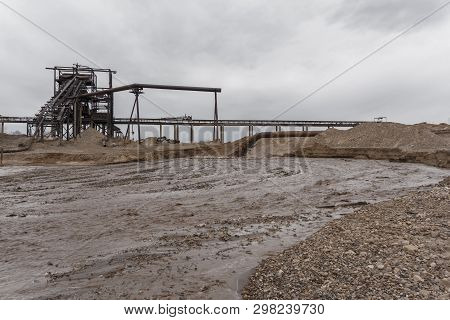 Rusty Pipe On The River Bank, From Which Sewage Flows, Dirty Sand Slurry, And Stationary Rusty Gravi