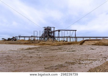 Rusty Pipe On The River Bank, From Which Sewage Flows, Dirty Sand Slurry, And Stationary Rusty Gravi