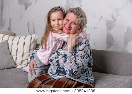 Grandmother And Her Little Granddaughter Are Watching Movies Together And Playing On The Device Whil