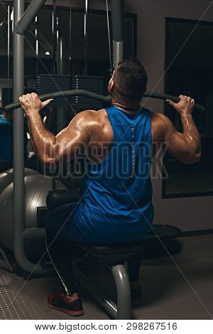 Strong Male Bodybuilder Doing Exercise For Back With Lat Pulldown Machine In Gym