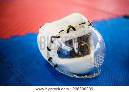White Protective Helmets With Clear Plactic Mask For Martial Arts On The Red Blue Floor