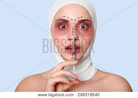 Portrait Of Woman In Clinic With Bandage On Head. Lady Holds Syringe. Lady With Opened Mouth Looks S