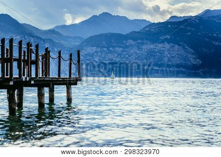 Summer Holiday: Wooden Dock Pier Over Blue Lake Water. Cloudy Evening Scenery.