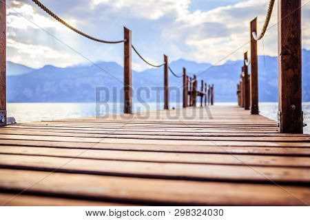 Summer Holiday: Wooden Dock Pier Over Blue Lake Water. Cloudy Evening Scenery.