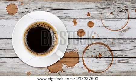Brown Cup Full Of Black Coffee On Saucer, With Ring Coffee Stains And Drops On White Painted Wooden 