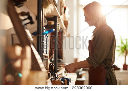 Side View Portrait Of Female Tanner Working With Leather In Workshop, Copy Space