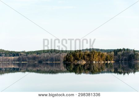 Small Tree Covered Island In Lake Illumintaed By The Rising Sun