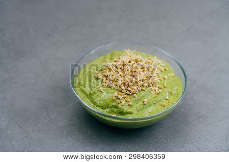 Bowl Of Green Smoothie Made Of Spinach With Buckwheat Sprouts On Grey Background. Vegan Food. Health