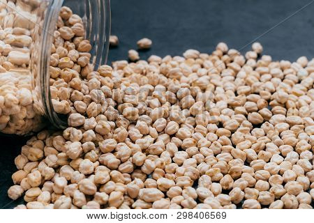 Glass Jar With Raw Garbanzo. Chickpea Grains Isolated On Dark Background. Close Up Shot. Protein See