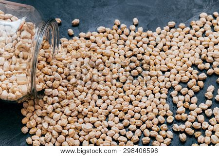 Chickpeas Spilled On Dark Background. High Protein Vegetarian Food. Garbanzo In Glass Jar. Vegan Hea