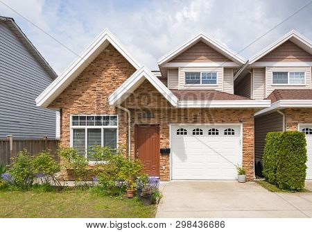 Half Of Residential Duplex House With Concrete Drive Way And Green Lawns In Front