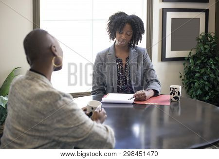 Black African American Female Businesswomen Talking In An Office.  The Two Women Looks Like A Start 