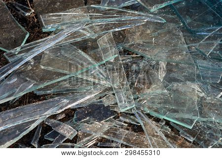 A Pile Of Different Sharp Pieces Of Broken Glass Lying On The Ground. Pieces Of Glass Of Different S