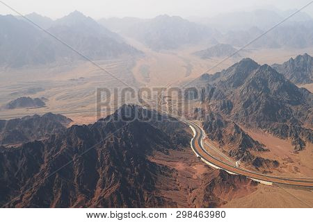 Aerial View Of A Highway Road Curving Between Treeless Rocky Mountains And Desert On The South Of Si