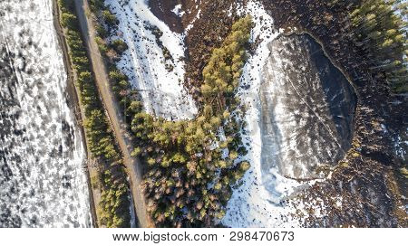 Aerial View Of Spring Rural Road In Yellow Pine Forest With Melting Ice Lake