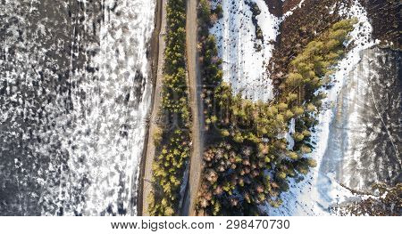 Aerial View Of Spring Rural Road In Yellow Pine Forest With Melting Ice Lake
