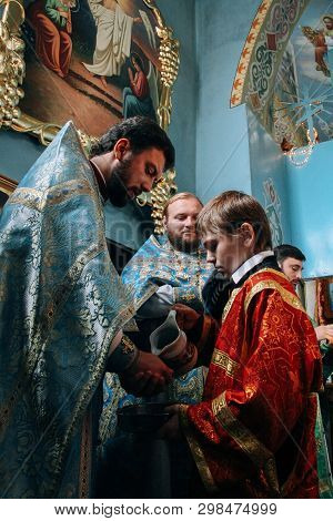 Voyutyn, Volyn / Ukraine - October 14 2008: Little Sexton Pours Water Into The Hands Of The Priest D