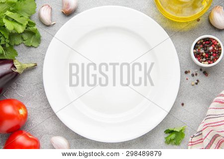 Empty White Plate In The Center, Ingredients Around. Eggplant, Tomatoes, Cilantro, Olive Oil, Spices