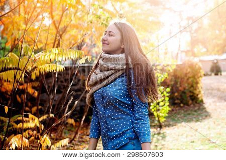 Cute Beautiful Smile Woman Walking In Red Autumn Park. Girl In Knitten Scarf Near Tree And She Is Ha