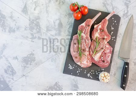 Two Piece Raw Meat On Cutting Board With Knife. Uncooked Fresh Pork Bone Steak With Garlic, Tomato A