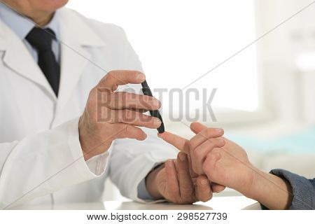 Doctor Taking Patient's Blood Sample With Lancet Pen In Hospital, Closeup. Diabetes Control