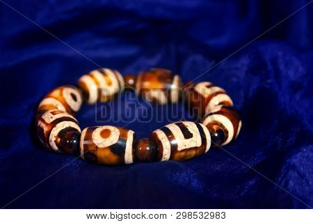 Bracelet : Tibetan Dzi Beads Bracelet, On Blue Background. Dzi Bead Is Considered To Provide Positiv