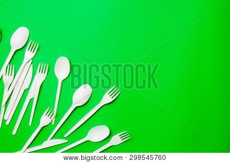 White Single-use Plastic Knives, Spoons, Forks On A Green Background. Say No To Single Use Plastic. 