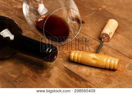 A Bottle Of Wine, A Glass, And An Old Corckscrew On A Wooden Table