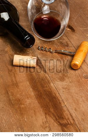 A Bottle Of Wine, A Glass, And An Old Corckscrew On A Wooden Table