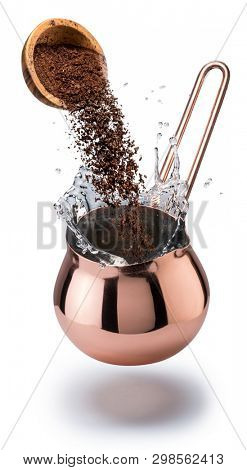 Coffee preparation. Conceptual photo - ground coffee falling into copper cerve. Clipping path.